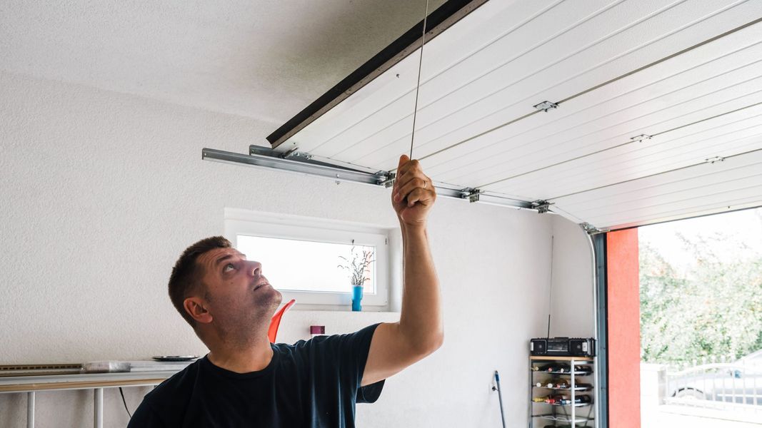 a man is holding a hose up to a window. features garage door services garage door repair garage door installation garage door spring repair provided by Retrak Door Service.