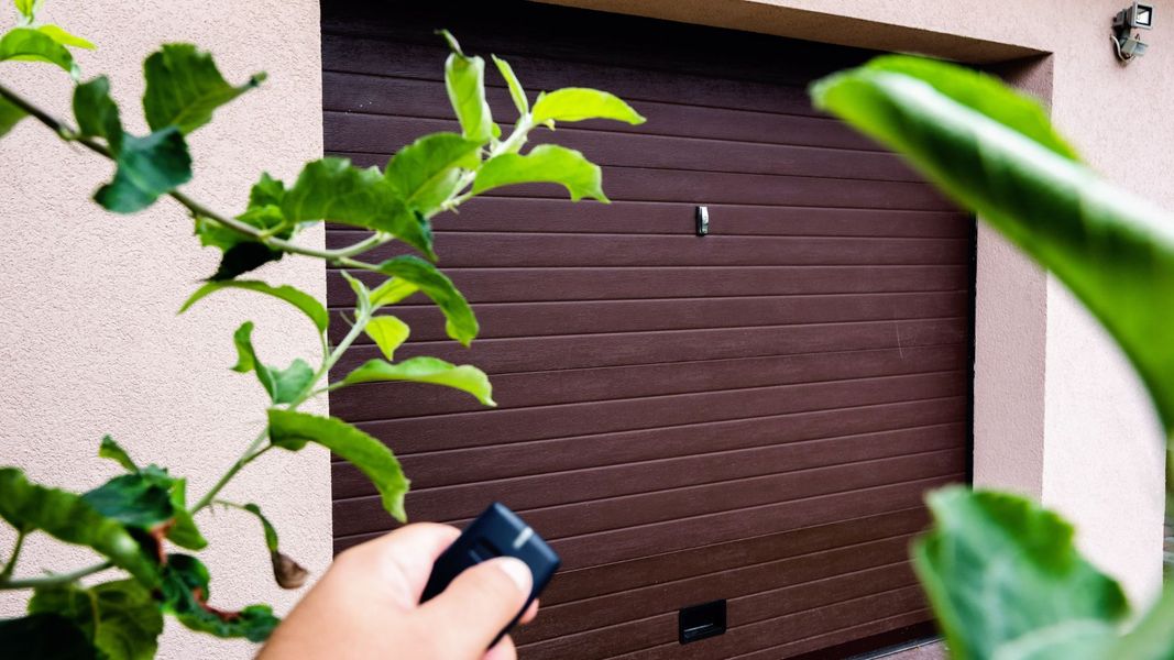 a person holding a cell phone in front of a window. features garage door services garage door repair garage door installation garage door spring repair new garage doors provided by Retrak Door Service.