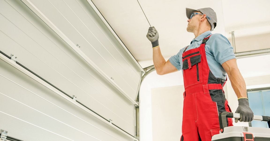 a man in a blue shirt is holding a ladder. features garage door services garage door repair garage door installation garage door spring repair provided by Retrak Door Service.