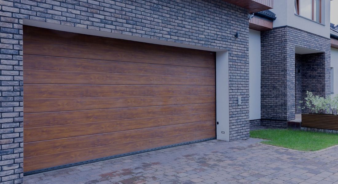 This scene from Lakewood, CO shows a brick building with a wooden door and a brick wall. with features such as garage door services garage door repair garage door installation garage door spring repair new garage doors.