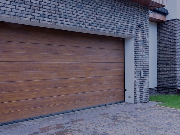 This scene from Lakewood, CO shows a brick building with a wooden door and a brick wall. with features such as garage door services garage door repair garage door installation garage door spring repair new garage doors.