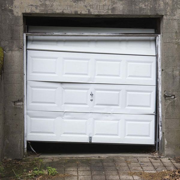 a white door is open on a brick wall. features garage door services garage door repair garage door installation garage door spring repair provided by Retrak Door Service.