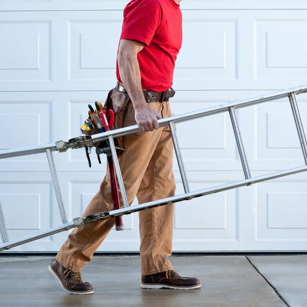 A man standing on a railing holding a pair of scissors. showcasing features like garage door services garage door repair garage door installation garage door spring repair new garage doors.