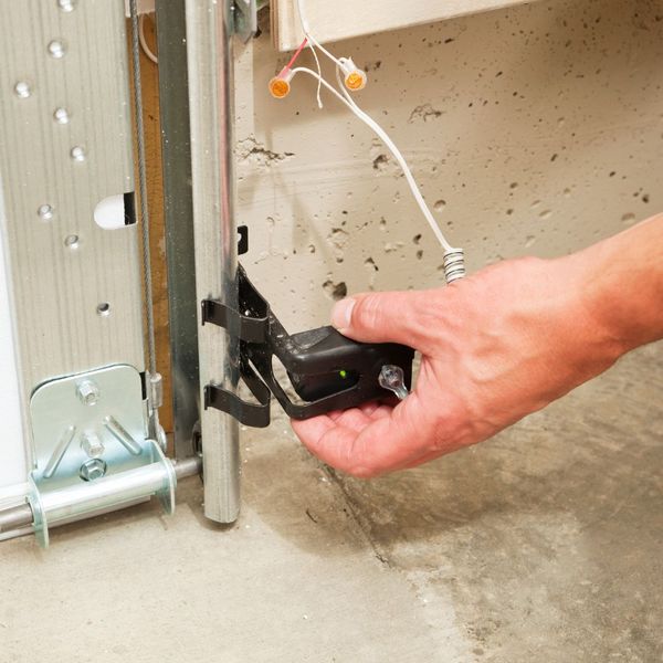 a person holding a cell phone in their hand. features garage door services garage door repair garage door installation garage door spring repair provided by Retrak Door Service.