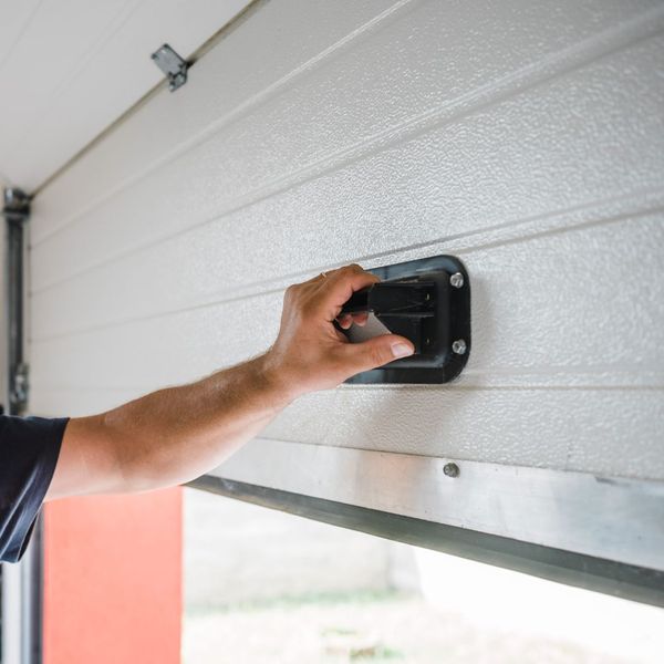 This scene from Lakewood, CO shows a man is using a small electrical device. with features such as garage door services garage door repair garage door installation.