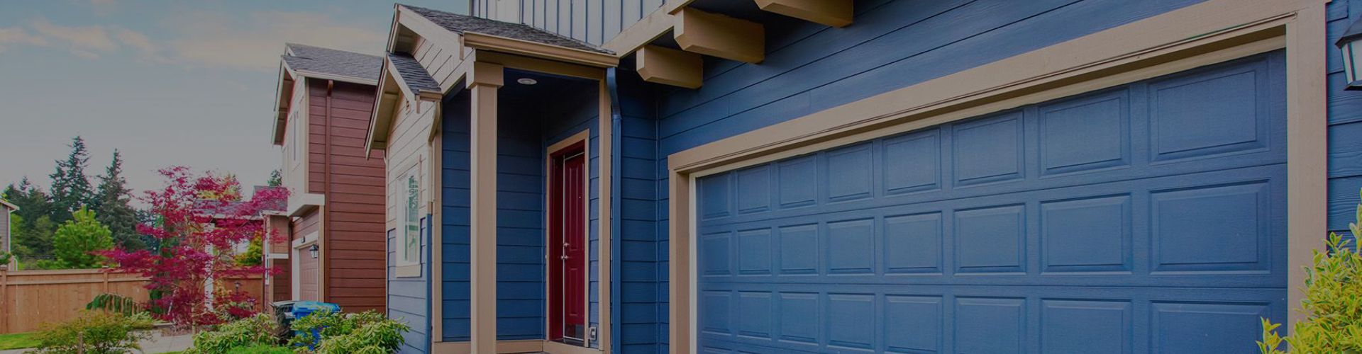 a blue house with a blue door and a blue wall. features garage door services garage door repair garage door installation garage door spring repair new garage doors provided by Retrak Door Service.