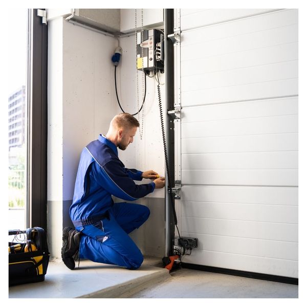 a man in a blue shirt is fixing a blue refrigerator. features garage door services garage door repair garage door installation garage door spring repair new garage doors provided by Retrak Door Service.