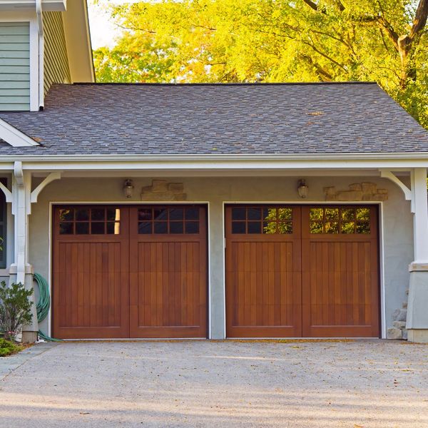 This scene from Lakewood, CO shows a white house with a wooden door and a black and white house. with features such as garage door services garage door repair garage door installation garage door spring repair new garage doors emergency garage door service.