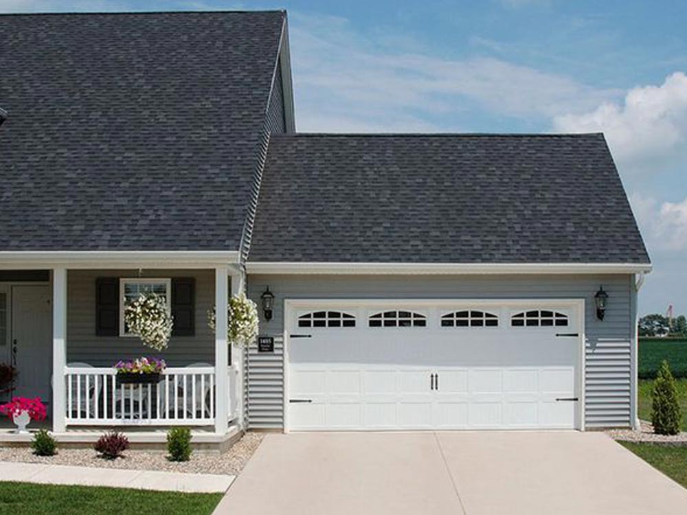 a white house with a blue door and a white house. features garage door services garage door repair garage door installation garage door spring repair new garage doors provided by Retrak Door Service.