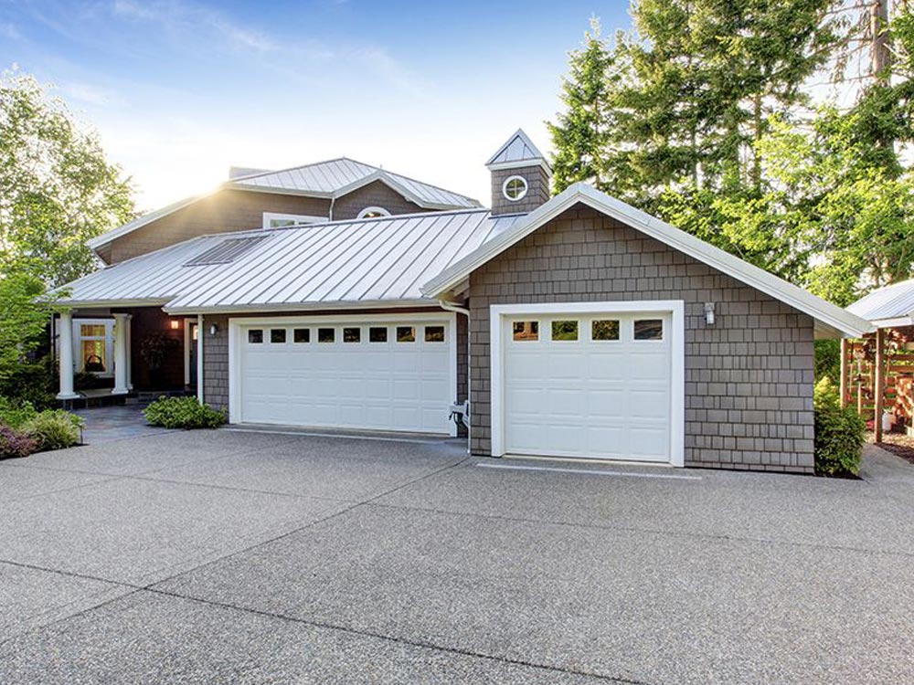 A white house with a blue roof and a white house. showcasing features like garage door services garage door repair garage door installation garage door spring repair new garage doors.