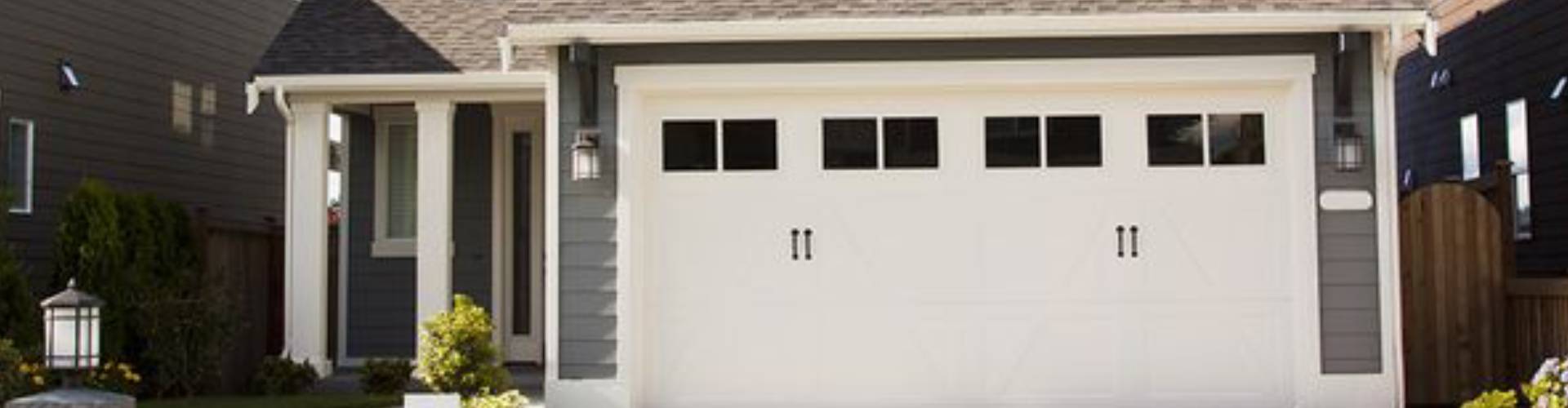 a white house with a blue door and a white fence. features garage door services garage door repair garage door installation garage door spring repair new garage doors provided by Retrak Door Service.