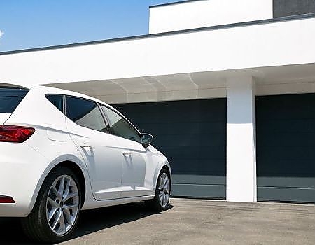 This scene from Lakewood, CO shows a white car parked in front of a white building. with features such as garage door services garage door repair garage door installation garage door spring repair.